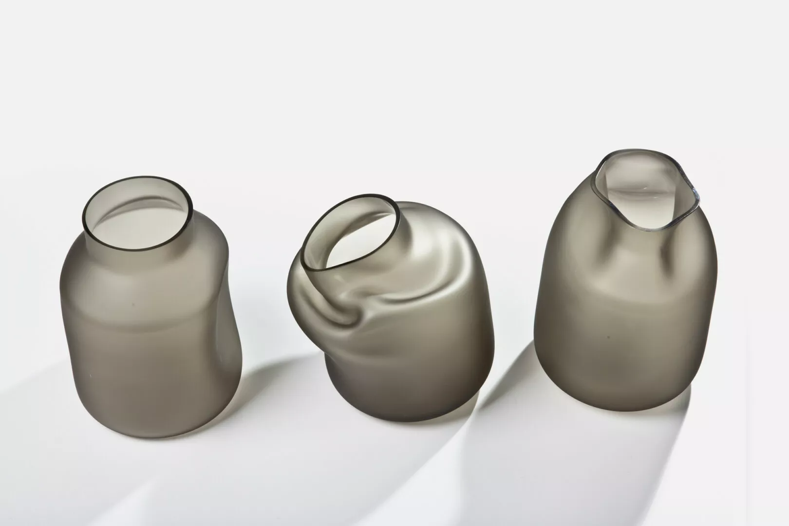 Three distorted glass vases on white background.