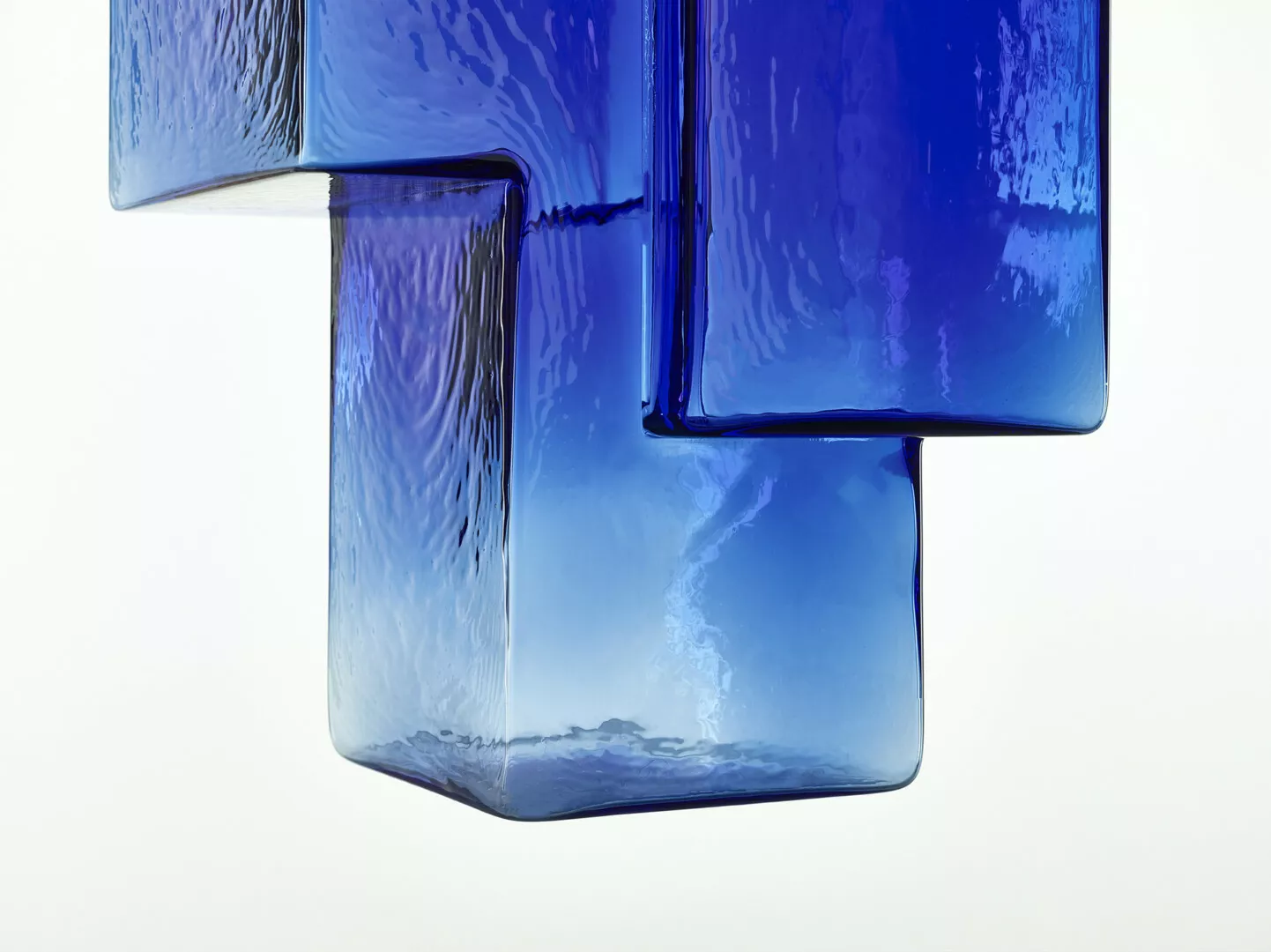 Abstract blue glass art installation on white background.