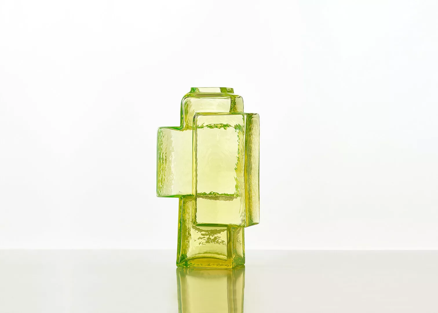 Translucent green glass cross sculpture on white background.