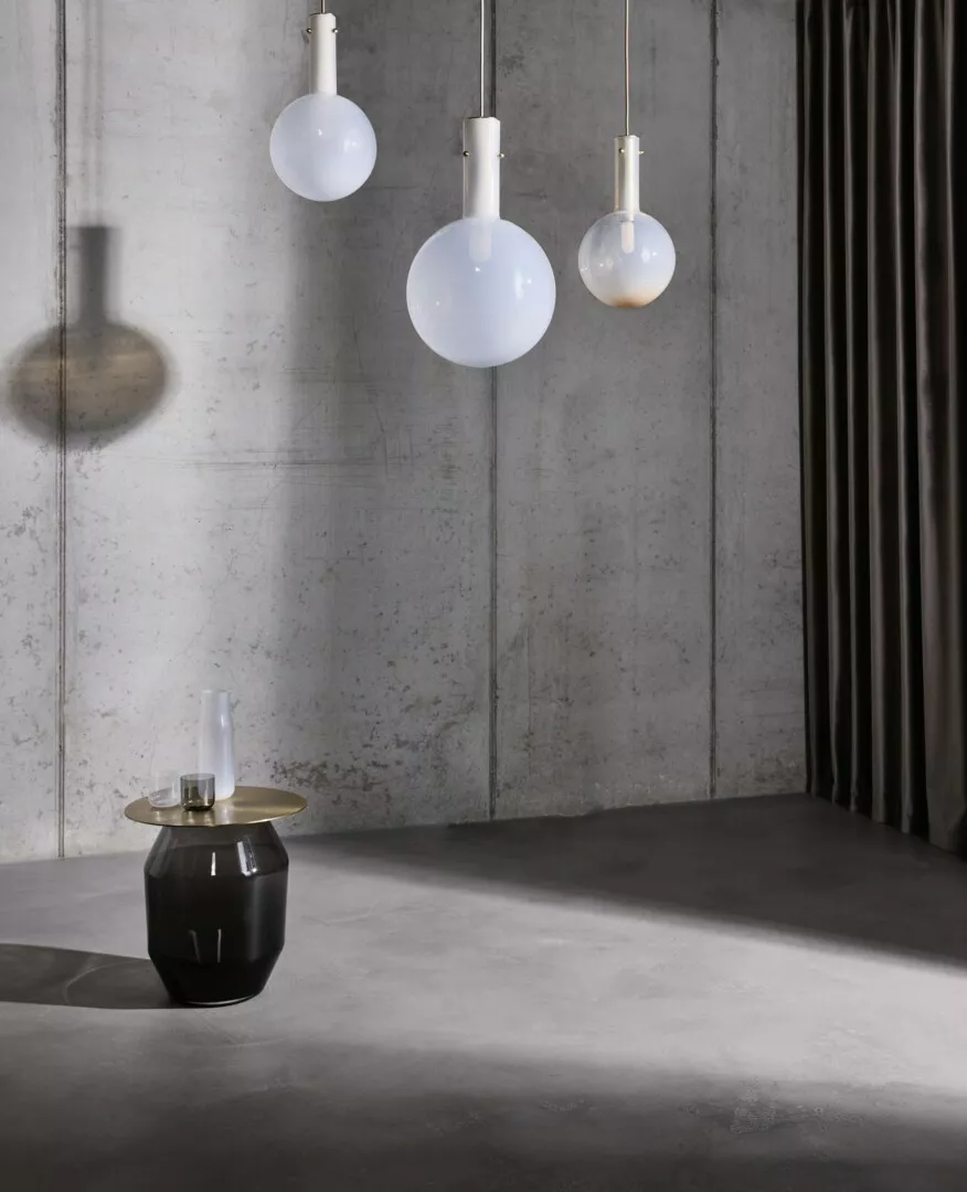Minimalist interior with hanging spherical lamps and black vase.
