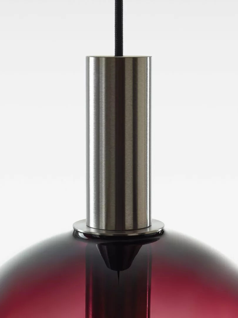 Close-up of modern cylindrical pendant light over red surface.