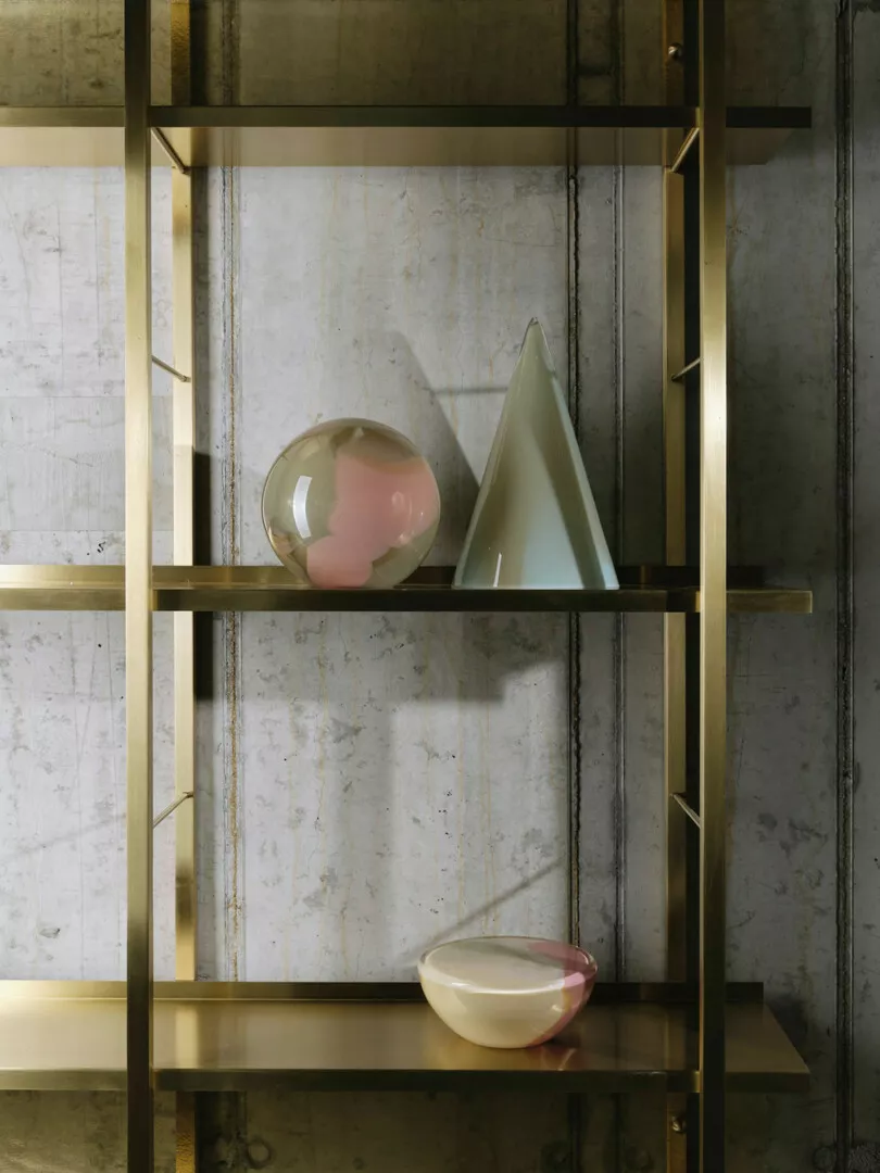 Modern shelf with decorative glass objects and marble background.