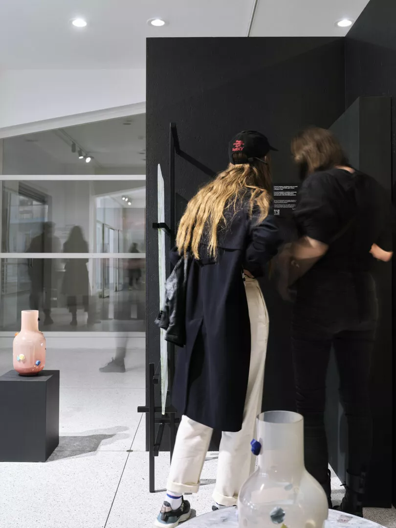 Visitors examining artwork at a modern gallery exhibit.