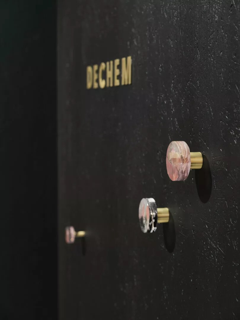 Glass knobs on black door labeled 'Dechem.'