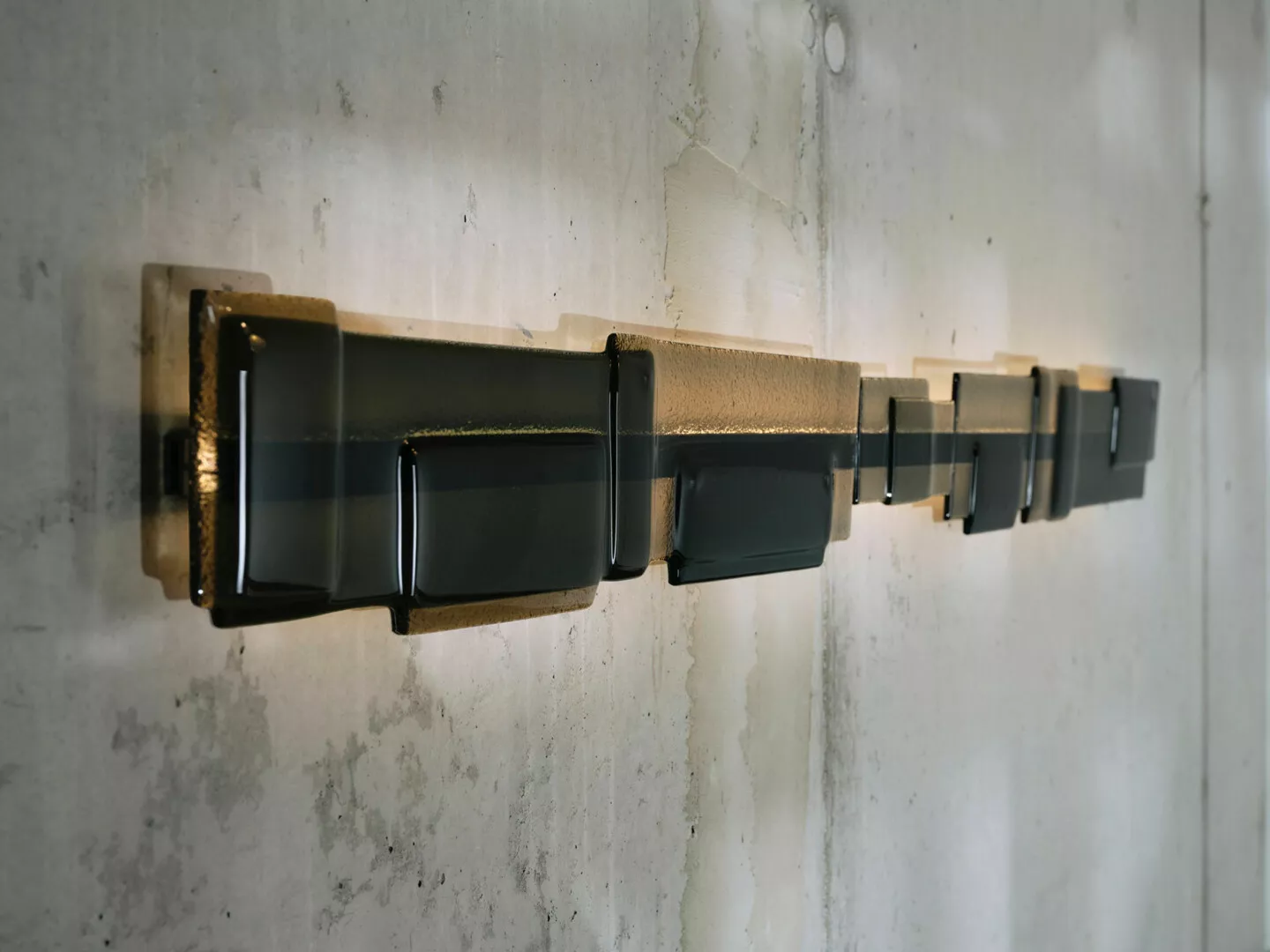 Row of modern black wall lamps against concrete.