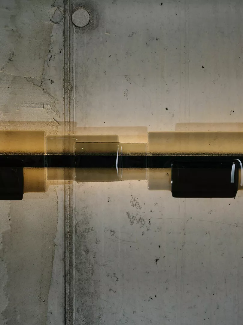 Concrete wall with water reflection and vertical shadows.