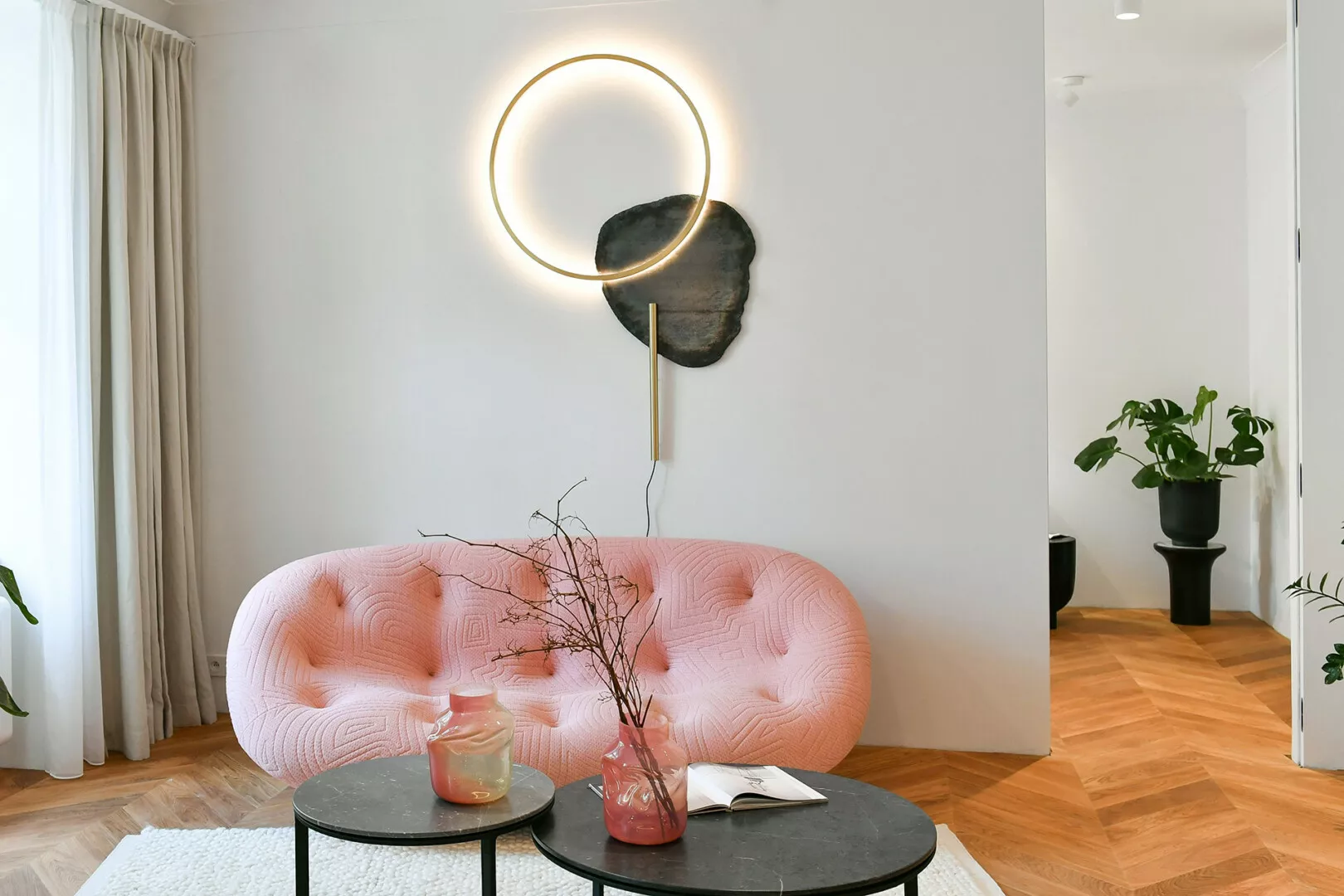 Modern living room with pink sofa and circular wall light.