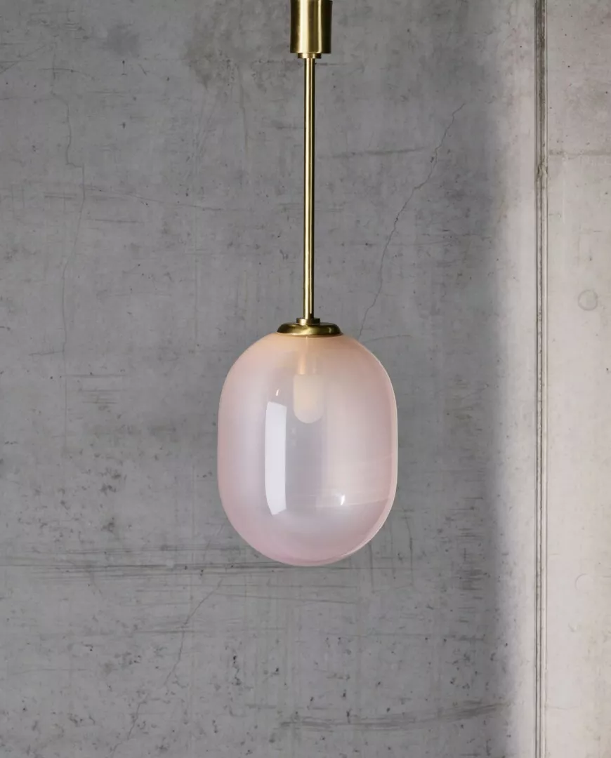 Pink glass pendant light against concrete background.