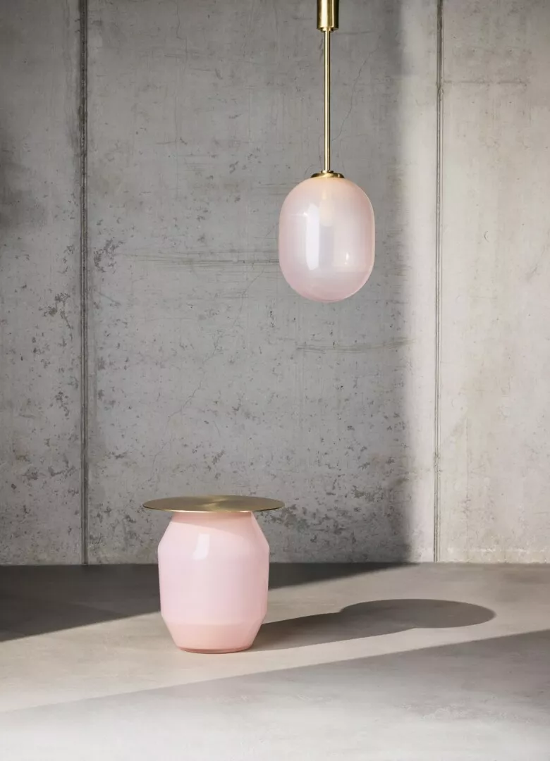 Pink pendant light and ceramic vase in minimalist setting.