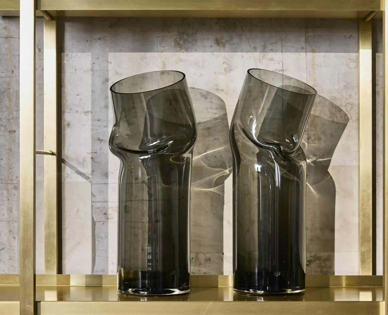 Two tall black glass vases on gold marble shelf.