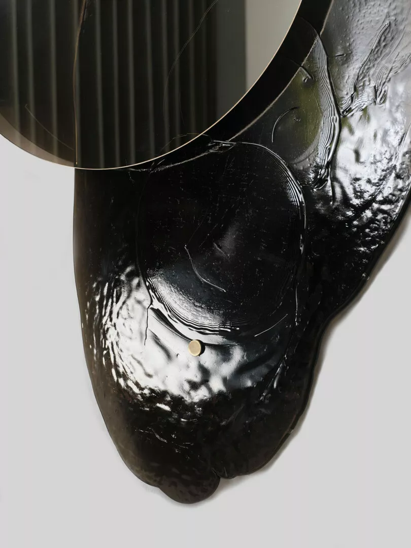 Curved black mirrored sculpture with abstract glossy surface.
