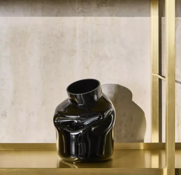 Black abstract ceramic vase on marble shelf.